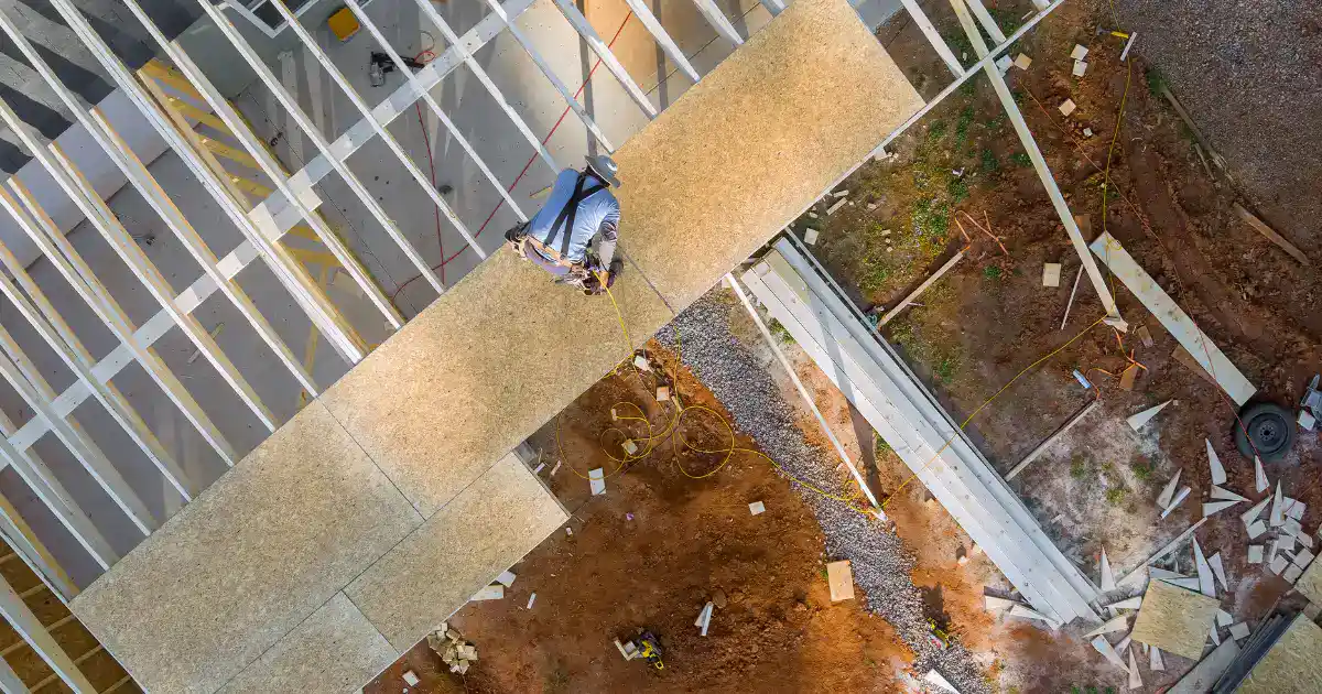 Construction workers completing commercial roof repair project with safety harnesses and scaffolding